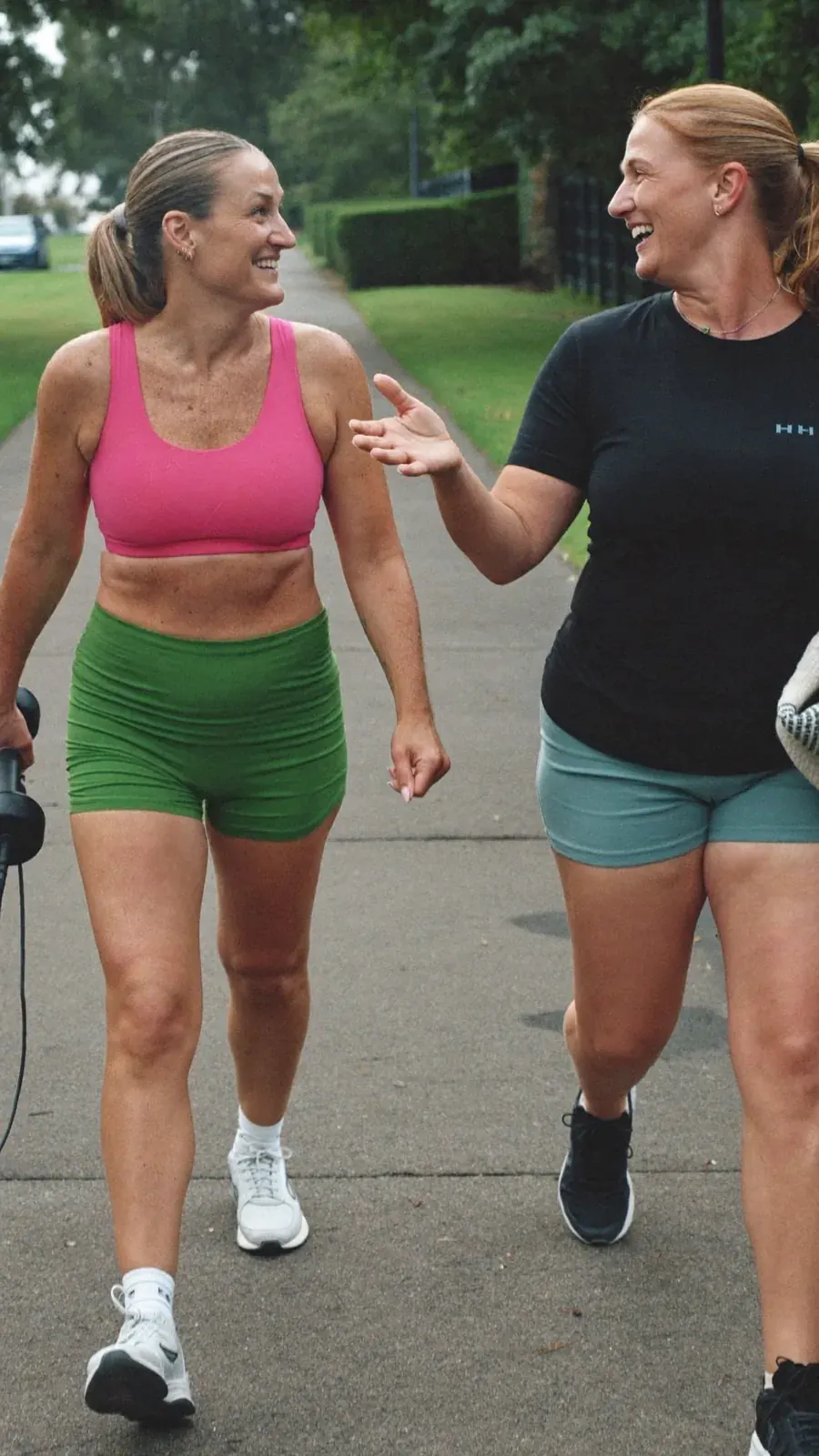 Dos mujeres vestidas de rosa y verde caminando al aire libre