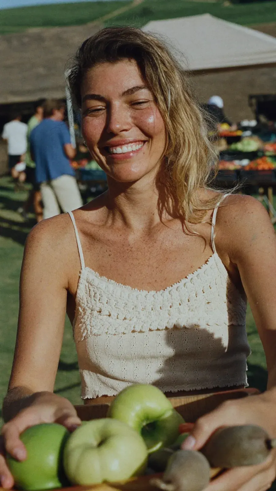 Woman at a farmers market holding a tray of green apples