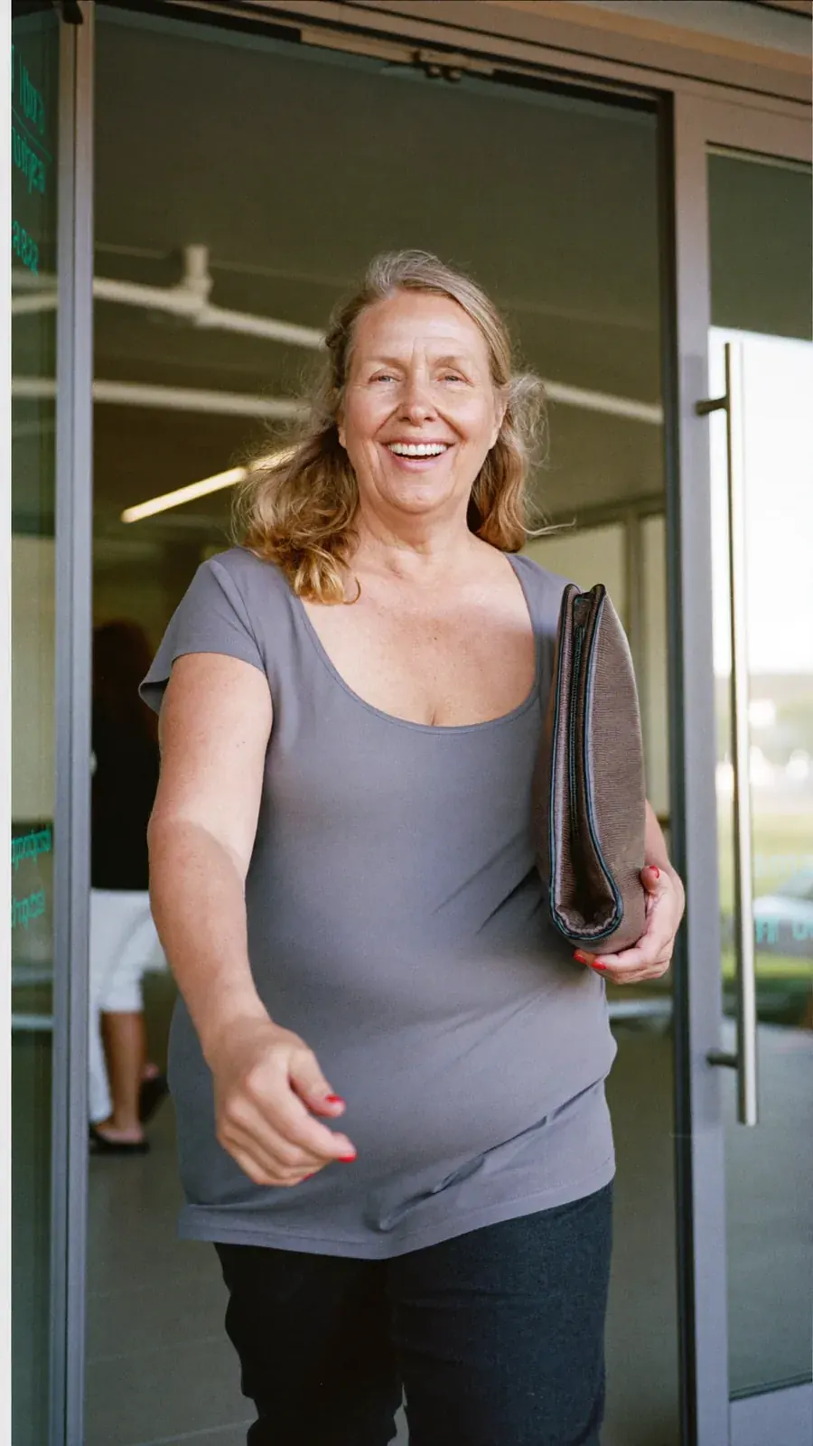 Mujer sonriendo junto a una puerta de cristal