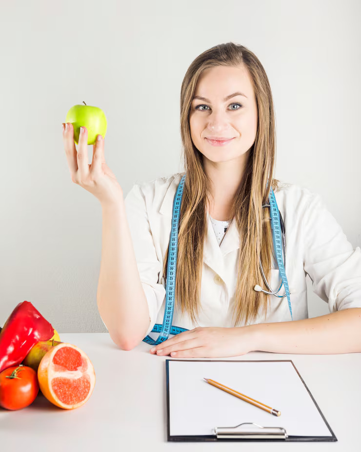 young-female-dietician-holding-green-apple-with-food-clipboard-desk_23-2147882184